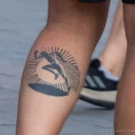 Татуировка с бегущим человеком в круге из лучей внизу левой ноги мужчины бегуна 2
