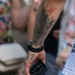 Фото тату на руке мужчины с тюремными татуировками: цифры, кресты, символы. Черно-белая татуировка на предплечье и кисти руки.
