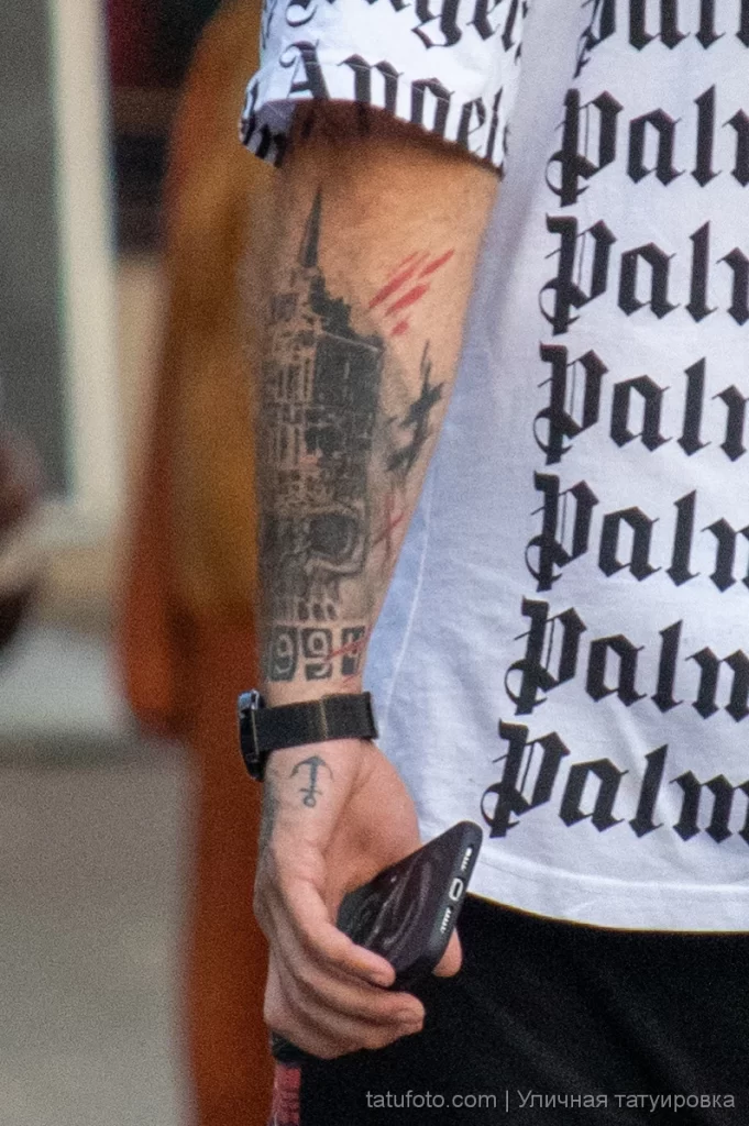 Татуировка с городским зданием и якорем на запястье левой руки мужчины 6