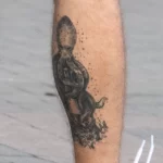 Татуировка с осьминогом на маяке внизу правой ноги парня 5