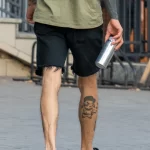 Татуировка с персонажем мультика Пикачу внизу ноги парня 11