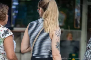 Фотография крупным планом татуировки на плече девушки, изображающей цветы и бабочек в черно-серых тонах.