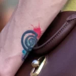 Татуировка со спиралью и красно синими кляксами на запястье левой руки девушки 2