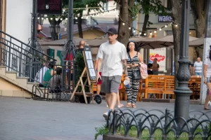 Фото мужчины с татуировкой на руке, идущего по улице. Татуировка в морском стиле, видны детали рисунка корабля и других символов.