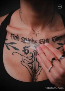 Фото тату надписи "Sad Birds Still Sing" и изображения птицы на груди девушки. Татуировка в память о близком человеке.