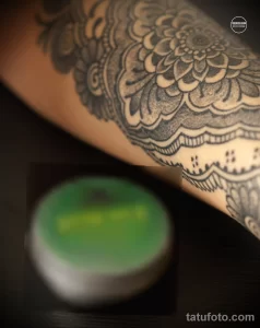 Фото татуировки на руке женщины: мандала в стиле dotwork, зеленый крем для татуировки. Детализированный рисунок татуировки, выполненный точками.