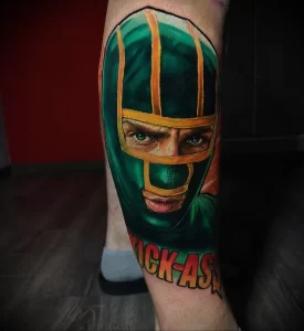 Фото тату на икре: гиперреалистичный портрет персонажа Judge Dredd из комиксов, с надписью 'Kick-Ass'.