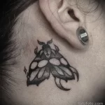 Фото татуировки на шее: изображение жука-носорога в стиле blackwork. Детализированный рисунок с использованием черных тонов.