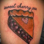 Фото тату с изображением кусочка вишневого пирога и надписью 'sweet cherry pie'. Яркий и сочный рисунок для любителей десертов.