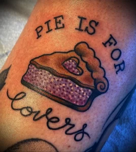 Фото тату на руке: кусок пирога с фиолетовой начинкой и надписью 'Pie Is For Lovers' в стиле олдскул.