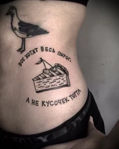 Фотография татуировки с изображением чайки, пытающейся украсть кусок пирога. Тату выполнено в черно-белом цвете с тонкими линиями и надписью на русском языке.
