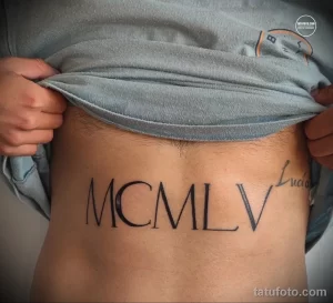 Фото татуировки на животе с римскими цифрами MCMLV и именем Lucia. Эскиз тату для тех, кто ценит историю и личные символы.