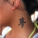 Фотография татуировки на шее с одним черным иероглифом. Изображение сделано в профиль, демонстрируя аккуратное нанесение татуировки.