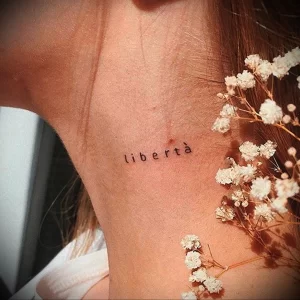 Фото тату: маленькая татуировка надписью 'libertà' (свобода) на ключице. Изящный шрифт и минималистичный дизайн.