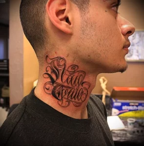 Фотография татуировки на шее мужчины с надписью «Stay Loyal» черными чернилами. Текст выполнен стилизованным шрифтом с декоративными элементами.