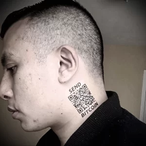 Фото тату QR-кода на шее мужчины с короткой стрижкой. Под кодом надпись 'SEND BITCOIN'. Оригинальный рисунок татуировки.
