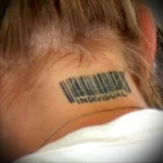 Фото тату: Черный штрихкод с надписью 'INDIVIDUAL' на затылке у человека со светлыми волосами. Минималистичный рисунок татуировки.