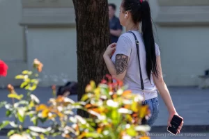 Фото татуировки на руке девушки, выполненной в темных тонах. Виден рисунок, напоминающий птицу или цветок. Идеальный эскиз тату для нежных и романтичных натур.