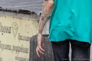 Фото тату на руке мужчины, выполненное в минималистичном стиле. Изображение состоит из нескольких линий и символов.