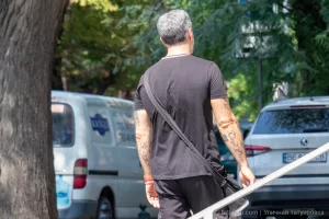 Фото тату: Мужчина с татуировками на предплечьях, включающими надписи, символы и рисунки в реалистичном стиле.