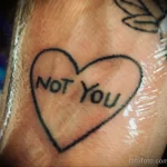 Фото тату сердца с надписью "NOT YOU". Минималистичный рисунок татуировки в черно-белой гамме.