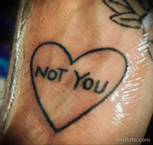 Фото тату сердца с надписью "NOT YOU". Минималистичный рисунок татуировки в черно-белой гамме.