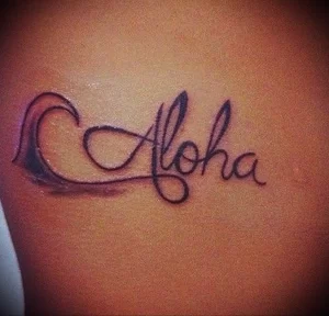 Фото тату надписи 'Aloha', стилизованной под волну. Изящные линии и плавные переходы создают эффект движения и легкости.