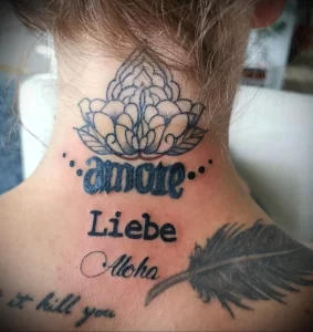 Фото тату на шее с изображением цветка, надписей 'amore', 'Liebe' и 'Aloha', выполненное в детализированном стиле с использованием ярких цветов.