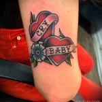Фото тату на руке с изображением сердца, пронзенного стрелой, и надписью 'CRY BABY'. Стиль татуировки - олдскул, традиционный.