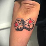 Фото тату двух игральных костей с сердечком на одной из граней. Простой и лаконичный рисунок татуировки в черно-красных тонах.