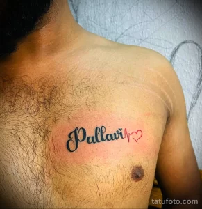 Фото тату: изящная надпись "Pallavi" с маленьким сердечком, выполненная черными чернилами на груди. Красивый рисунок татуировки.