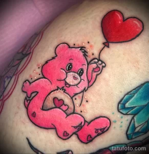 Фото тату розового Care Bear с воздушным шаром в форме сердца на руке. Яркий и позитивный рисунок в стиле мультфильма.