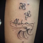 Фото тату с надписью 'Aloha', изображением волны и цветов на руке. Красивый и символичный дизайн, отражающий любовь к морю и гавайской культуре.