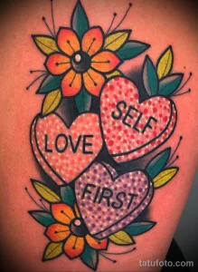 Фото тату на плече: три сердца с надписями 'Love Self First' и цветами в стиле олд скул. Яркие цвета и детальная проработка.