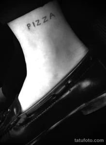 Фото тату: простая и стильная татуировка с надписью 'Pizza', выполненная на лодыжке в черном цвете.