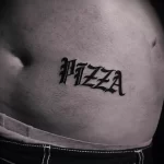 Фото тату: стильная татуировка с надписью 'Pizza', выполненная в оригинальном шрифте леттеринг на животе.