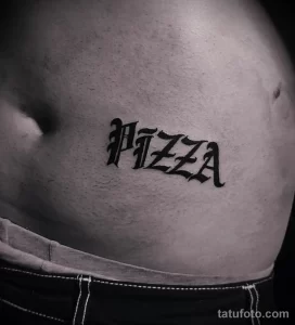 Фото тату: стильная татуировка с надписью 'Pizza', выполненная в оригинальном шрифте леттеринг на животе.