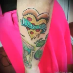 Фото тату кусочка пиццы в форме сердца с надписью 'I LOVE PIZZA', выполненное в ярких цветах на руке. Романтичный и аппетитный эскиз тату.