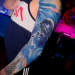 голубая татуировка на тему космоса на всю левую руку парня