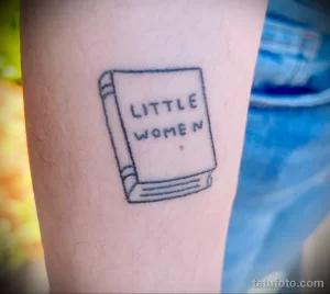 Фото татуировки на руке с изображением книги 'Little Women'. Простой рисунок, тонкие линии, черно-белое изображение.