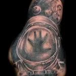 чёрно-белый рисунок татуировки с шлемом скафандра на кулаке