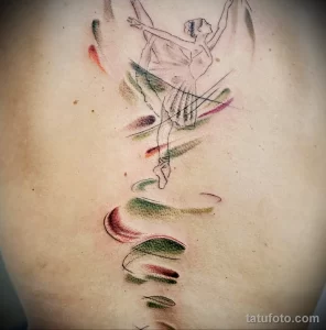 Фото тату на боку с изображением танцующей балерины, выполненной в технике акварели. Нежные пастельные тона и размытые линии.