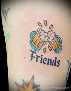 Фото татуировки с изображением двух кружек пива и надписью 'Friends'. Яркий, красочный рисунок на предплечье.