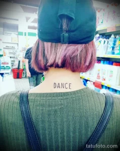 Фото татуировки с надписью "DANCE" на шее. Простой, но вдохновляющий дизайн. Идеально для тех, кто любит танцевать и верит в силу движения.