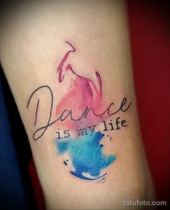 Фото тату: акварельная татуировка с надписью 'Dance is my life' и изображением танцующей девушки, выполненная в нежных розовых и голубых тонах. Красивый эскиз тату для танцовщиц.
