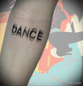 Фото тату: татуировка с надписью 'DANCE', выполненная в гранжевом стиле с использованием черных чернил и эффекта потертости. Стильный эскиз тату для любителей танцев.