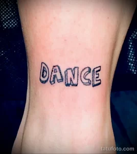 Фото тату: минималистичная татуировка с надписью 'DANCE', выполненная черными чернилами на запястье. Простой и стильный эскиз тату для любителей танцев.