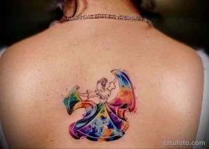 Фото татуировки на спине с изображением танцующей балерины, выполненной в технике акварели. Яркие цвета и плавные переходы создают эффект волшебства.