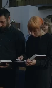 Фото татуировки в виде маленькой птицы на ключице девушки. Рисунок выполнен в черном цвете.