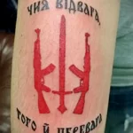 Фото тату: две винтовки и надпись на украинском языке на предплечье. Патриотический рисунок татуировки в красных тонах.
